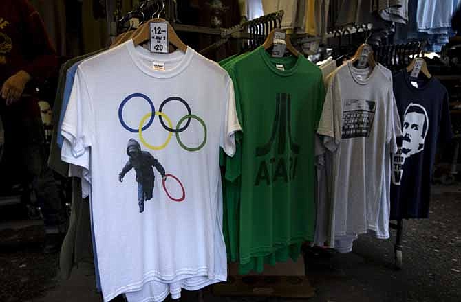 In this photo taken Monday, July 16, 2012, a t-shirt depicting a rioter holding an Olympic ring is displayed on sale in a London market. The guardians of the games are vigilant about protecting the integrity - and the commercial clout - of the Olympic brand. But even they can't stop the irreverent spirit of artists and craftspeople, who have responded to the games with a cheeky mix of celebration, skepticism and satire. 