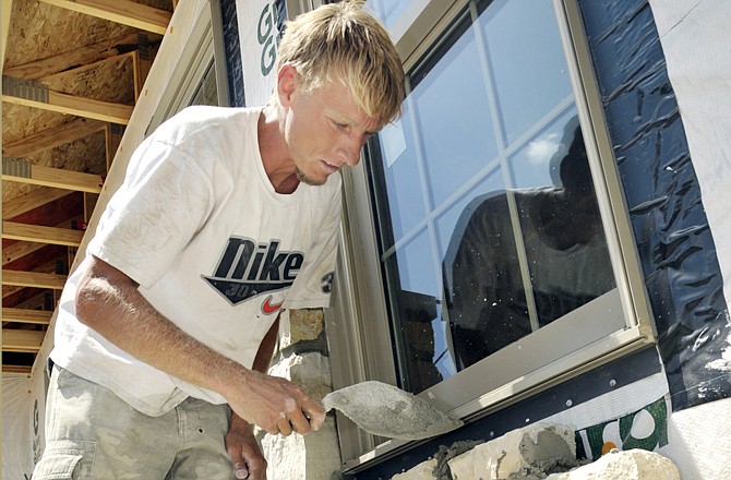 Dave Smith of Smith Brick and Stone adds another layer of stone to the front of the home being constructed for the Tyler Huffman family.