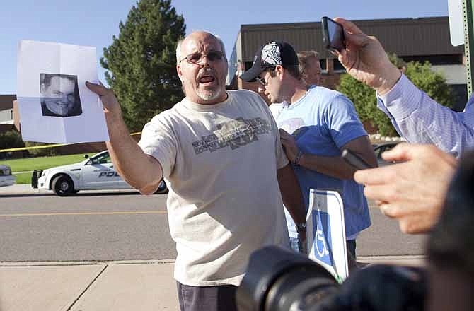 Tom Sullivan , holds a photograph of his son, Alex Sullivan, as he pleads with the media to help him find his son, outside Gateway High School on Friday, July 20, 2012 in Aurora, Colo. The family later confirmed that Alex Sullivan was killed while celebrating his 27th birthday by attending the midnight premiere of the Batman movie Friday morning. A gunman wearing a gas mask set off an unknown gas and fired into the crowded movie theater killing 12 people and injuring at least 50 others, authorities said. 