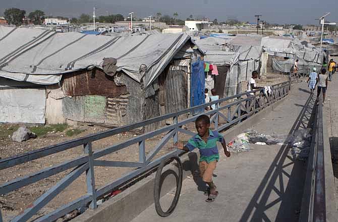 In this Wednesday, June 13, 2012 photo, a boy rolls a bicycle tire up a ramp near a camp for people displaced by the 2010 earthquake in Port-au-Prince, Haiti. Amid the horrors of Haiti's 2010 earthquake lay a promise of renewal. With the United States taking the lead, international donors pledged billions of dollars to help it "build back better," breaking its cycle of dependency. Yet 2 1/2 years later, the fruits of an ambitious $1.8 billion U.S. reconstruction promise are hard to find.