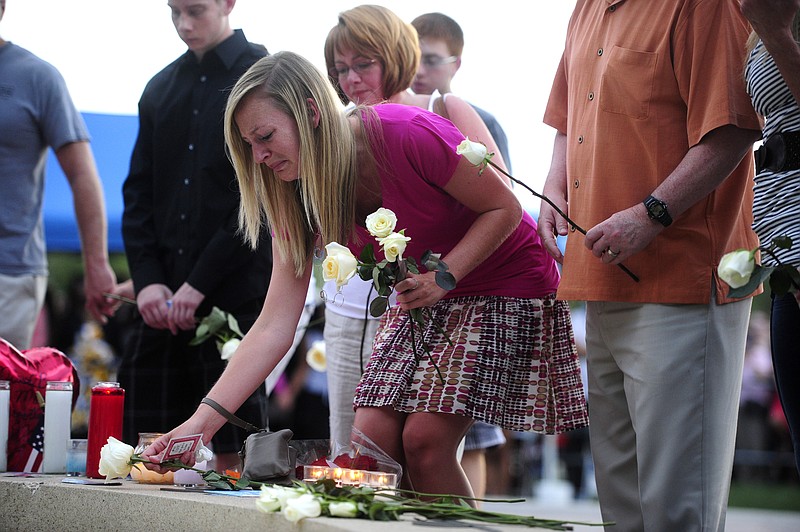 Family members of the victims of the Century 16 theater shooting leave roses Sunday at a memorial display during a vigil at the Aurora Municipal Center campus in Aurora, Colo.