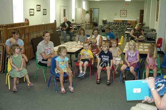 Children aged two to four and their parents and friends listen as Library Director Connie Walker reads "I Could Be, You Could Be" at the library during storytime.