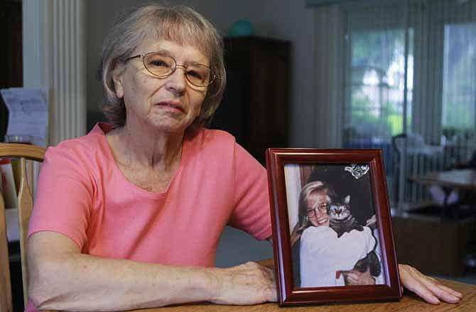 In this July 17, 2012 photo, JoAnn Zywicki sits by a photo of her daughter Tammy at her home in Ocala, Fla. Two decades after her daughter Tammy was stabbed to death along an Illinois highway while returning to college in Iowa, the case remains unsolved.