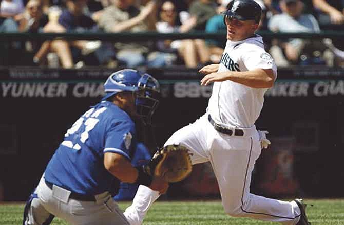 Seattle Mariners' Kyle Seager, right, comes in to score as Kansas City Royals catcher Brayan Pena waits for the throw in the third inning of a baseball game on Saturday, July 28, 2012, in Seattle. 