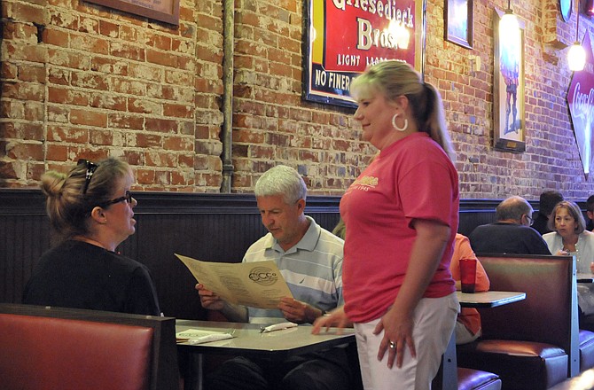 Ecco Lounge owner Sally Powell, standing, visits with customers Barb and Sid Belshe during lunchtime last week. The Belshes are regular diners at the restaurant and enjoy visiting with Powell, who tries to talk to each of her customers.