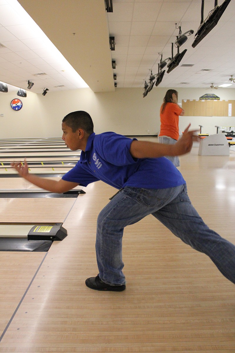 12-year-old Isaiah Mackley follows through on a strike at Fulton Bowling Center Monday. The boy took 13th in the International Family Tournament with his grandfather in Jupiter, Fla., and gold at the Show-Me State Games with his stepfather, Jim Boone.