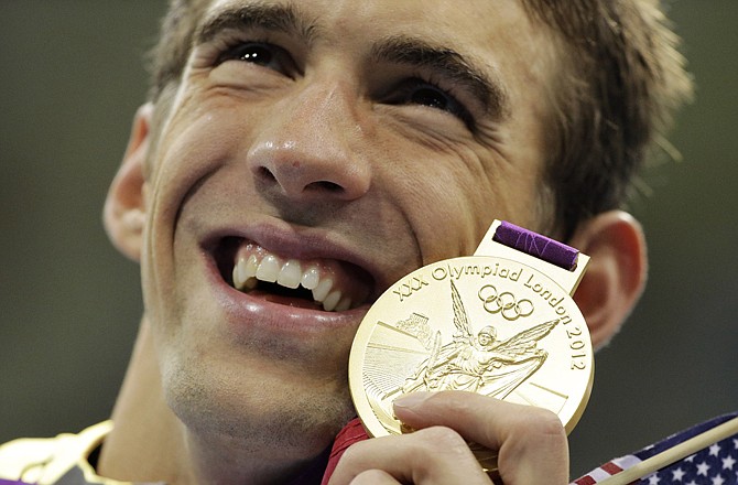 Michael Phelps poses with his gold medal Tuesday after he was part of the winning 4x200-meter freestyle relay team at the Aquatics Centre in London.