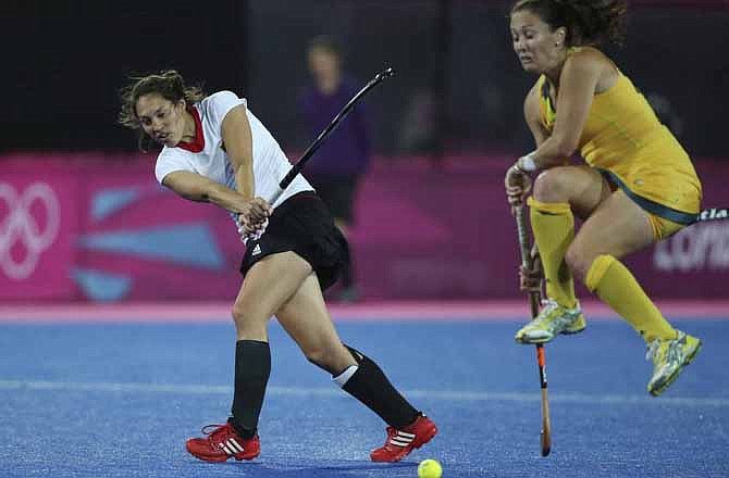 Germany's Mandy Haase, left, plays a shot as Australia's Hope Munro tries to avoid being hit by the ball during their women's hockey preliminary round match at the 2012 Summer Olympics, Tuesday, July 31, 2012, in London. With today's digital delivery of information in real time, it's become increasingly more difficult to watch  Olympic events on a recorded delay without already knowing the outcome.