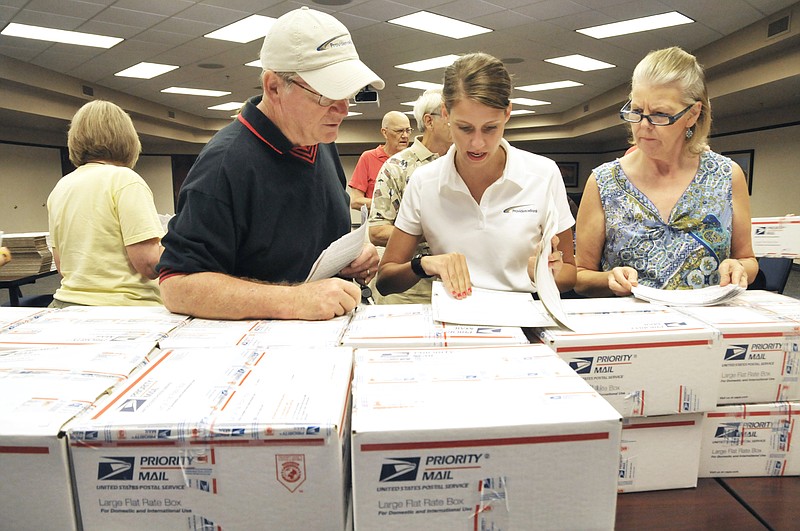 Harry Kennedy, left, Marie Tustin and Kathy Lea check the labels on boxes being readied to be shipped overseas to people serving in the U.S. military. The Providence Bank PALs Club provided volunteers assisted by bank personnel to get the items packed, labeled then delivered to the post office.