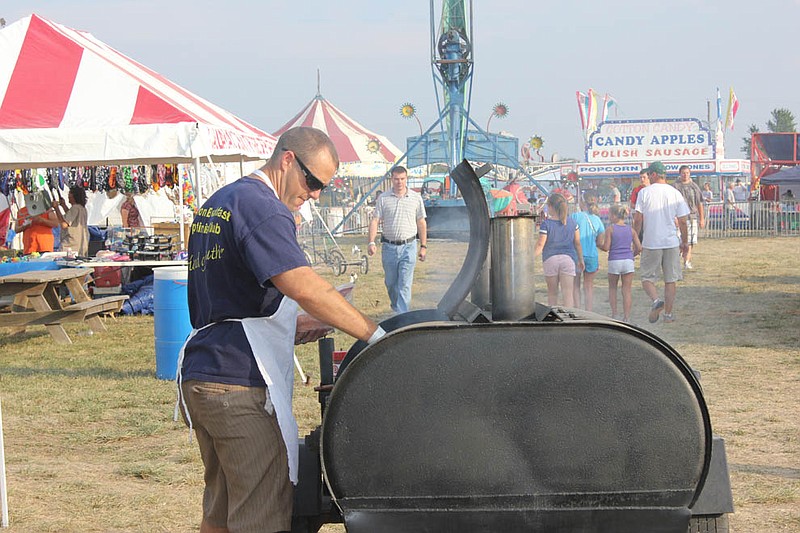 A Breakfast Optimist cooks up hot dogs outside of their vendor booth at the county fair Wednesday.