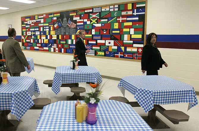 In an April 22, 2008 file photo, U.S. Immigration and Customs Enforcement officials, Marc Moore, left, and Gary Mead, center, along with Corrections Corporation of America Administrator, Evelyn Hernandez, right, talk about a mural of flags as well as the table cloths and flowers added to the cafeteria at the T. Don Hutto Residential Center in Taylor, Texas, during a tour for the media. The U.S. is locking up more illegal immigrants than ever before, generating a lucrative business for the nation's largest prison companies.