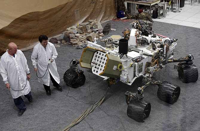 Engineers work on a model of the Mars rover Curiosity at the Spacecraft Assembly Facility at NASA's Jet Propulsion Laboratory in Pasadena, Calif., Thursday, Aug. 2, 2012. After traveling 8 1/2 months and 352 million miles, Curiosity will attempt a landing on Mars the night of Aug. 5, 2012.