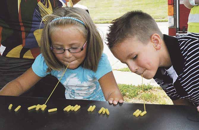 Emily and Chance Herrera try to pick up noodles with spaghetti during games at the Back 2 School Jam on Lafayette Street between Elm and Dunklin Streets on Saturday. 