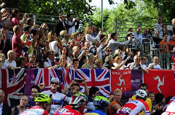 In this Saturday July 28, 2012 photo, spectators cheer as the men's cycling road race starts on the Mall in London during the 2012 Summer Olympics. 