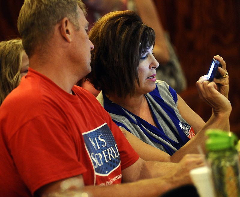Cole County Western District Commissioner candidate Kris Scheperle, left, and his wife, Jennifer, use their iPhone to keep tabs on Tuesday's Cole County election results as they roll in while attending an election watch party at Prison Brews.