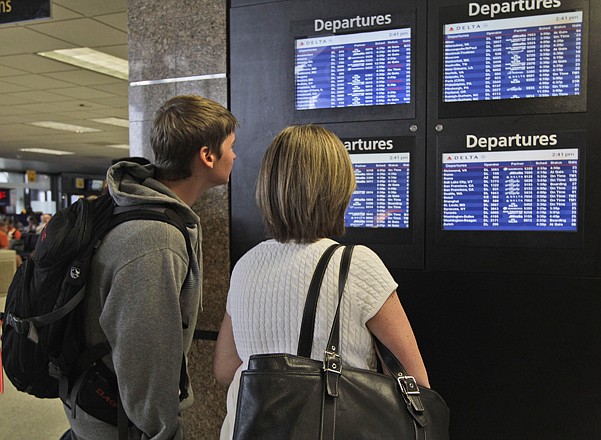 Passengers check the departing flights at the Delta Air Lines terminal at JFK International airport in New York. The government says nearly 84 percent of domestic flight arrived within 15 minutes of their scheduled time in the first half of this year.