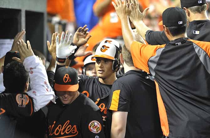 Baltimore Orioles' Manny Machado, center, is congratulated by the team after hitting a three-run home run against the Kansas City Royals in the sixth inning of a baseball game Friday, Aug. 10, 2012, in Baltimore.