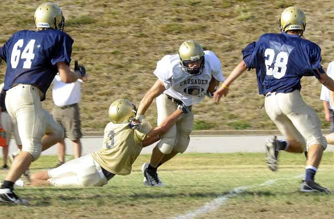 Helias running back Michael Tannehill tries to break the grasp of Cole Distler during Friday night's scrimmage at the school.