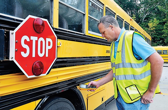 Frank Underwood, First Student location manager, uses an electronic inspection device (EID) to check one of 10 electronic inspection points on the bus. Each bus is assigned a EID wand for daily inspections.