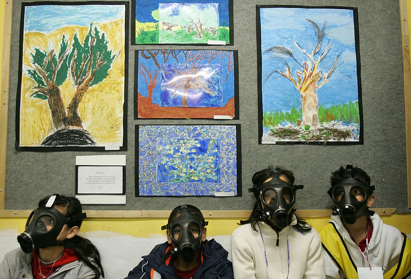 Israeli school children wear gas masks during a drill organized by the Israeli Home Front Command simulating a chemical missile attack in a shelter at a school in the central Israeli city of Lod. Israel's outgoing civil defense chief said Wednesday that an attack on Iran's nuclear sites would likely trigger a drawn-out war that would last months and kill hundreds of Israelis.