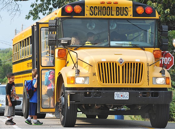 In this August 16, 2012 photo, Jonathan Chase, left, waits his turn to board the bus behind fellow riders on their way to Cedar Hill Elementary School.