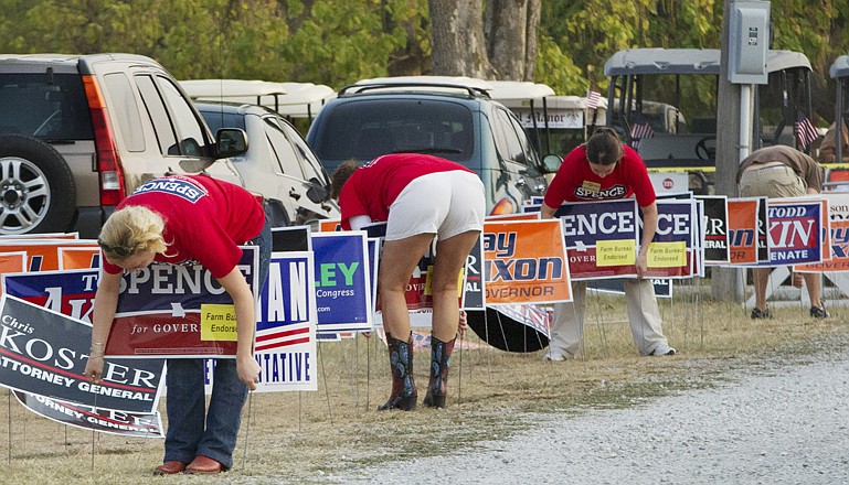 Campaign supporters place signs Thursday near the entrance to the Governor's Ham Breakfast at the Missouri State Fair in Sedalia.