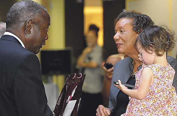 Lincoln University's retiring president Carolyn Mahoney holds her 2-year-old granddaughter Cindy Hirano while chatting with Dr. Johnny Houston at her retirement ceremony Wednesday. 