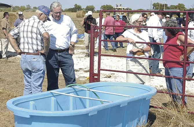 Clarksburg Farms owners Charles Rackers, far left, and Carol Rackers, far right, talk with Mo. Gov. Jay Nixon and first lady Georganne Nixon on Wednesday as they check out the water flow from a new well. 