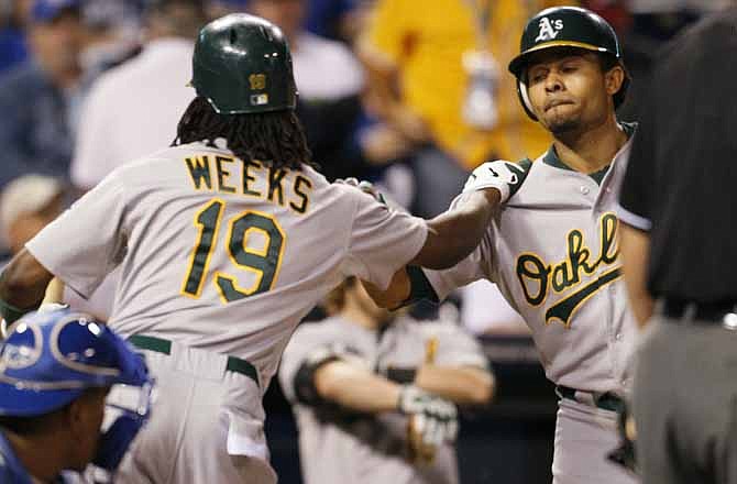 Oakland Athletics' Coco Crisp (4) is congratulated by Jemile Weeks (19) after hitting a home run off of Kansas City pitcher Luke Hochevar in the sixth inning at Kauffman Stadium in Kansas City, Mo., Thursday, Aug. 16, 2012. Originally ruled as a double, a replay review determined Crisp's hit was interfered with by a fan, resulting in the homer. 