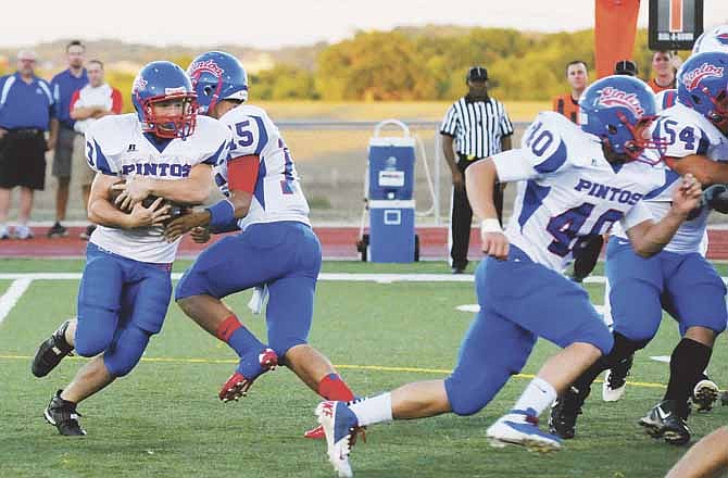 With Jerry Lutz (40) leading the way, California running back Seth Fairchild takes a handoff from quarterback Jaden Barr and heads for the hole during Friday's action with Moberly in the Jamboree at the Falcon Athletic Complex in Wardsville, Mo.