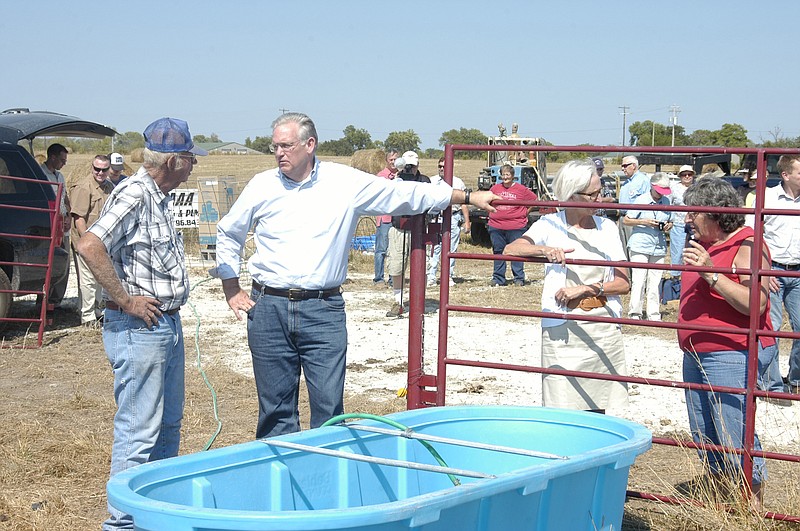 Charles Rackers, left, speaks to Gov. Jay Nixon on Wednesday, Aug. 15,  as they check out the flow from the new cost-share well on the Rackers' Clarksburg Farms. The governor has visited several farms to look at the new wells.  