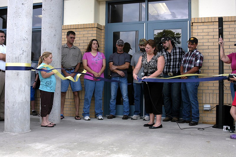 Latham School Administrator Tanya Brown cuts the ribbon for the new school facility as members of the school board look on.