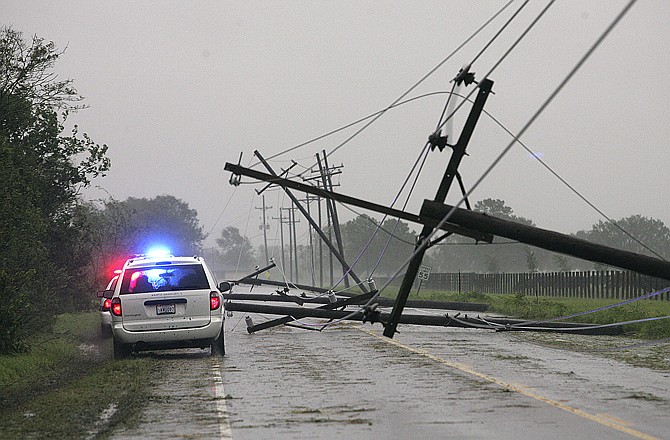 Lafourche Parish Sheriff's Office vehicles drive pass downed power lines Wednesday near the Valentine Bridge in Houma, La.