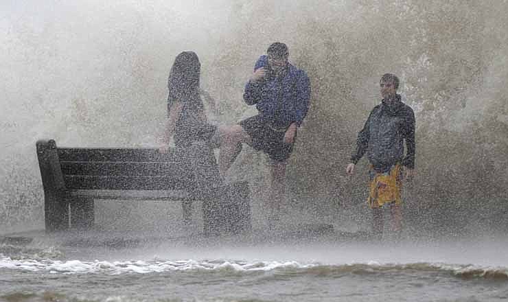 People walk in the storm surge from Isaac, on Lakeshore Drive along Lake Pontchartrain, as the storm approaches landfall, in New Orleans, Tuesday, Aug. 28, 2012. The storm was arriving at the seventh anniversary of Hurricane Katrina, which devastated Louisiana and Mississippi when it struck on Aug. 29, 2005.