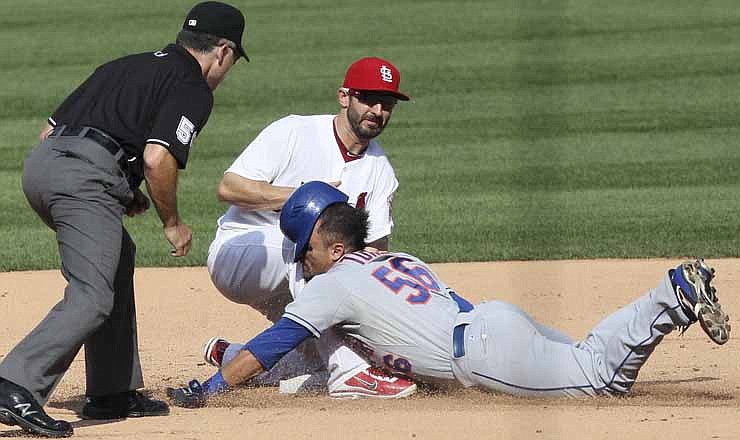 New York Mets' Andres Torres slides into second base ahead of the tag by St. Louis Cardinals shortstop Daniel Descalso in ninth inning of their baseball game, Monday, Sept. 3, 2012, in St. Louis. At left is second base umpire Dan Iassogna. On appeal, the first base umpire ruled that Torres failed to step on first base enroute to second and was called out. 