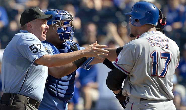 Home plate umpire Mike Everitt (57) steps between Kansas City Royals catcher Brayan Pena and Texas Rangers' Nelson Cruz (17) during the eighth inning of a baseball game at Kauffman Stadium in Kansas City, Mo., Monday, Sept. 3, 2012. Cruz was hit by a pitch on the play. 