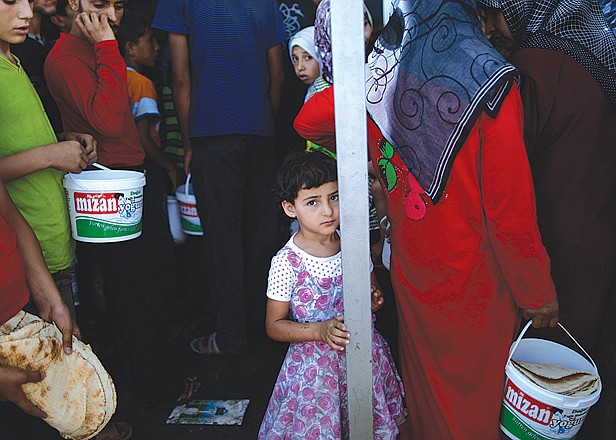 A Syrian girl, who fled her home because of fighting between the Syrian army and the rebels, waits her turn Monday to buy bread and eggs from a store as she and others take refuge at the Bab Al-Salameh border crossing, in hopes of entering one of the refugee camps in Turkey.