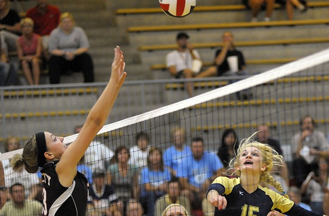 Makenzy Kliethermes of Jefferson City (left) and Erica Haslag of Helias battle for control of the ball at the net during Tuesday night's match at Fleming Fieldhouse.