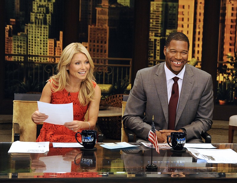 Former football player Michael Strahan, right, and host Kelly Ripa during Strahan's guest-host appearance on "Live! with Kelly," earlier this year in New York. Strahan is getting a permanent job in morning television as Kelly Ripa's co-host. Strahan replaces Regis Philbin on the syndicated "Live! With Kelly" show, adding his name to the title.