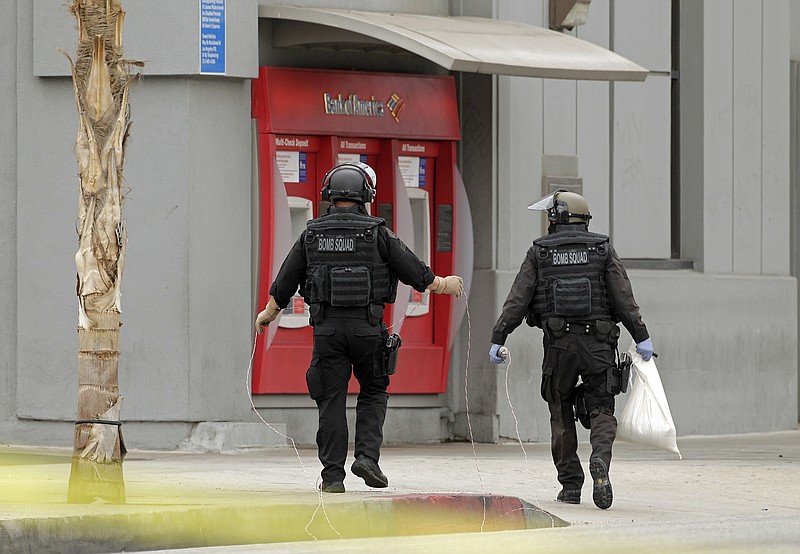 Los Angeles Police bomb squad members check for explosive devices Wednesday outside a Bank of America branch in Los Angeles. Authorities say two gunmen kidnapped a bank manager, held her overnight and strapped a device to her stomach before robbing a Bank of America. The woman then had employees take money from the bank and put it outside.