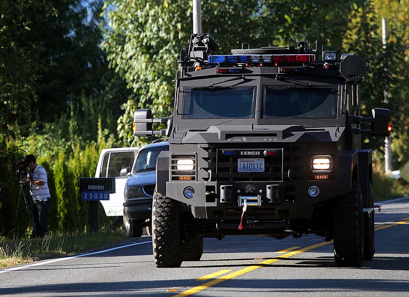 An armored law enforcement vehicle approaches a roadblock Sunday at the site of where a sniper in the woods shot a man and then later opened fire on a SWAT team, on Jim Creek Road near Arlington, Wash.