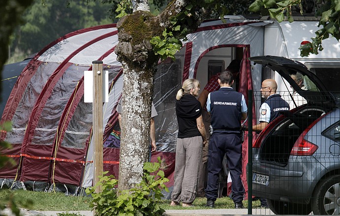 Investigators talk at the camp site Thursday where a family was vacationing near Annecy, France, before they were killed. Immobilized with fear, a 4-year-old British girl huddled for eight hours beneath the legs of a slain family member in the back of a car filled with corpses. 