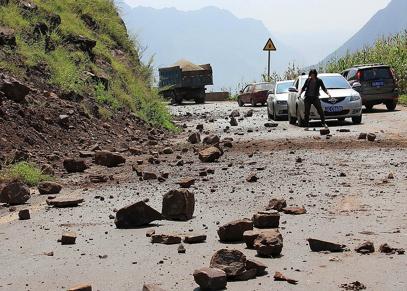 A woman tries to clear the fallen rocks from the mountain Friday on a road near Zhaotong town, Yiliang County, southwest China's Yunnan Province. A series of earthquakes collapsed houses and triggered landslides in a remote mountainous part of southwestern China. At least 67 deaths have been reported.