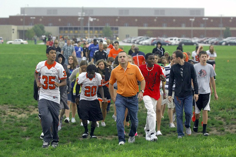 Normal Community High School students are led by a teacher to a nearby church as students were evacuated Friday after shots were fired in a classroom at the high school in Normal, Ill. Authorities say police have taken two people into custody. No one was injured.