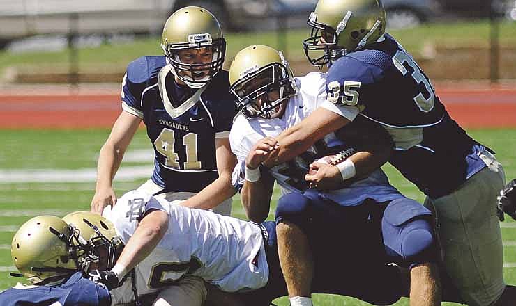Helias linebacker Justus Schulte wraps up Quincy Notre Dame running back Nick Weiman during Saturday's game at Adkins Stadium. Looking on for the Crusaders are Nick Haslag (9) and Shane Colonius (41). 