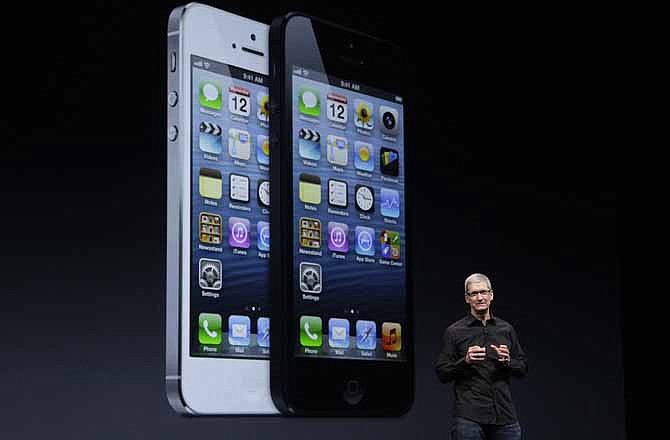 Apple CEO Tim Cook speaks in front of an image of the iPhone 5 during an Apple event in San Francisco, Wednesday, Sept. 12, 2012. 