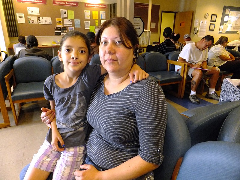 Claudia Pedroza, 39, and her eight-year-old daughter Karla Osorio at the Jefferson Action Center in Lakewood, Colo. Pedroza moved to the Denver suburbs five years ago with her husband and four children in hopes of a more comfortable suburban life. But Pedroza's family struggles to make ends meet and she was waiting with her on Monday to apply for help with food, toiletries and seek a new frying pan. 