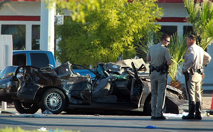 Police officers stand near a vehicle involved in a crash Thursday at a bus stop in Las Vegas. Police suspect a driver was drunk and speeding Thursday morning when his vehicle went airborne, spun out and plowed into the bus stop, killing four pedestrians and injuring eight others. 