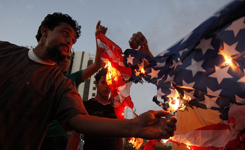 A Libyan follower of Ansar al-Shariah Brigades burns the U.S. flag Friday during a protest in front of the Tibesti Hotel, in Benghazi, Libya, Friday, Sept. 14, 2012, as part of widespread anger across the Muslim world about a film ridiculing Islam's Prophet Muhammad.