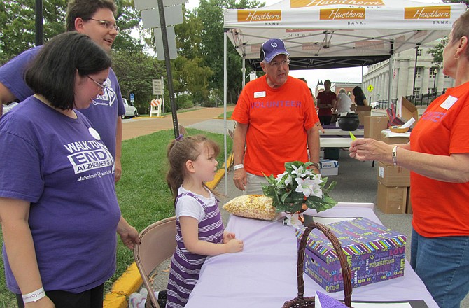 Walk to End Alzheimer's co-chair Carol Benna, right, reads the name of a prize winner after Mai-Lin Clardy, 4, picked the name from a box. At left are her parents, Mika and John Clardy. In the background is the other event co-chair, Reg Turnbull.